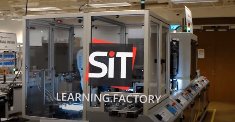 A wide shot of an industrial laboratory at the Singapore Institute of Technology (SIT), featuring modular manufacturing stations enclosed in glass, labeled "LEARNINNG FACTORY."